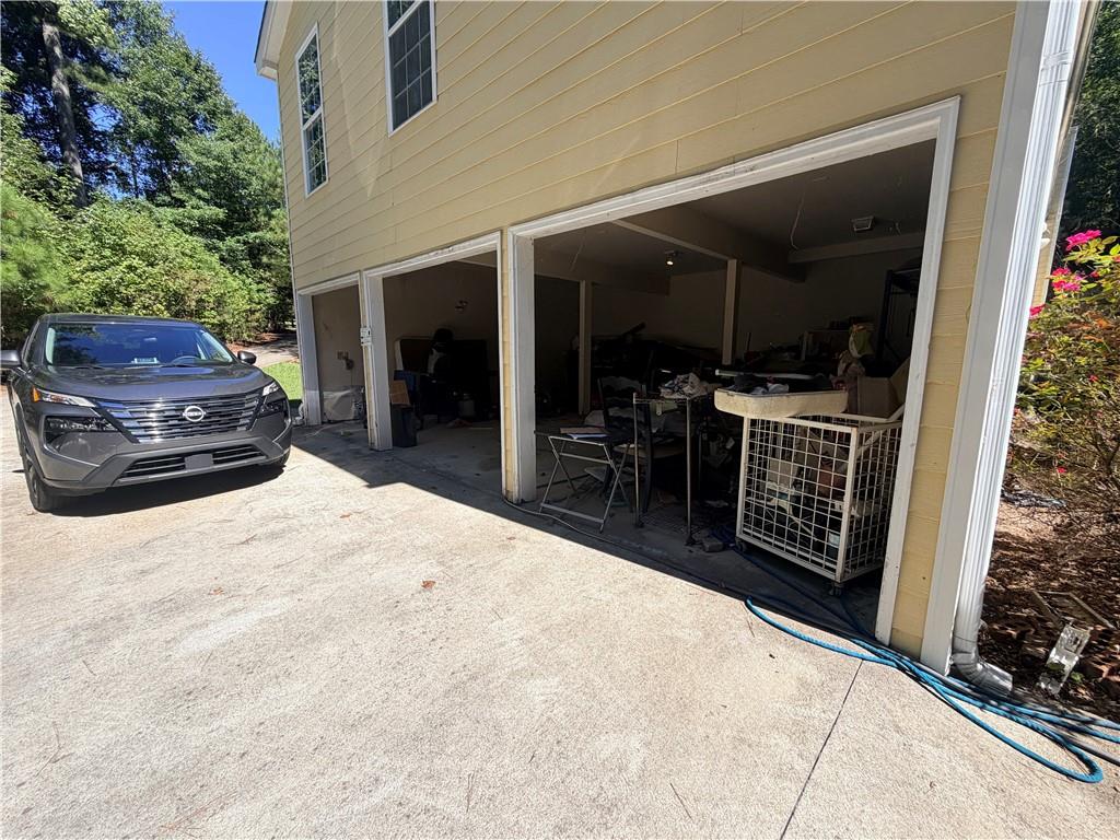 House exterior with open, storage-filled garage doors and a dark SUV on the driveway.
