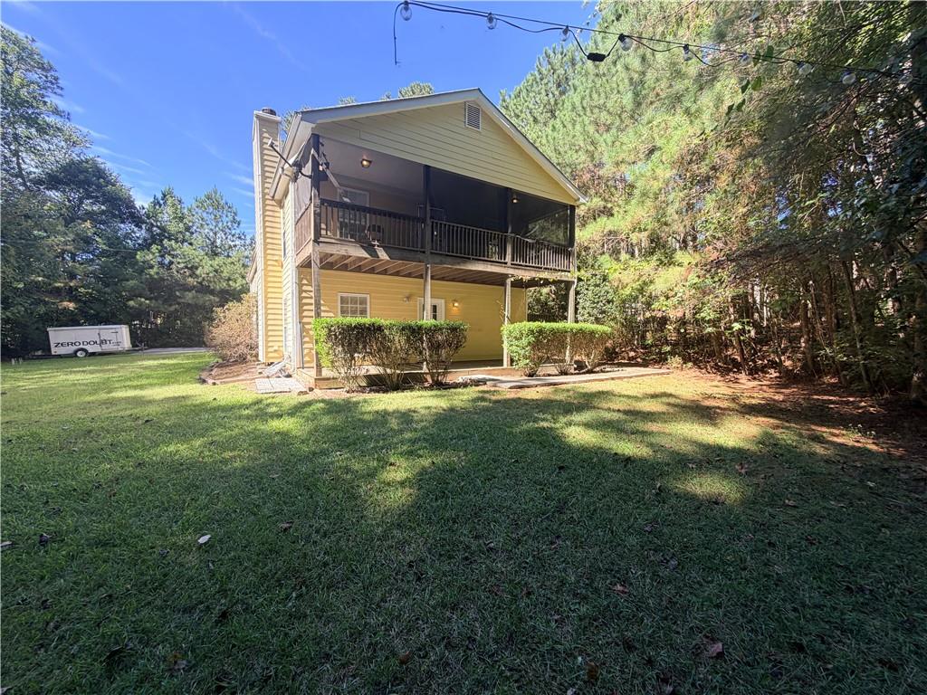 Yellow two-story house with a screened balcony overlooking a grassy, tree-lined yard.
