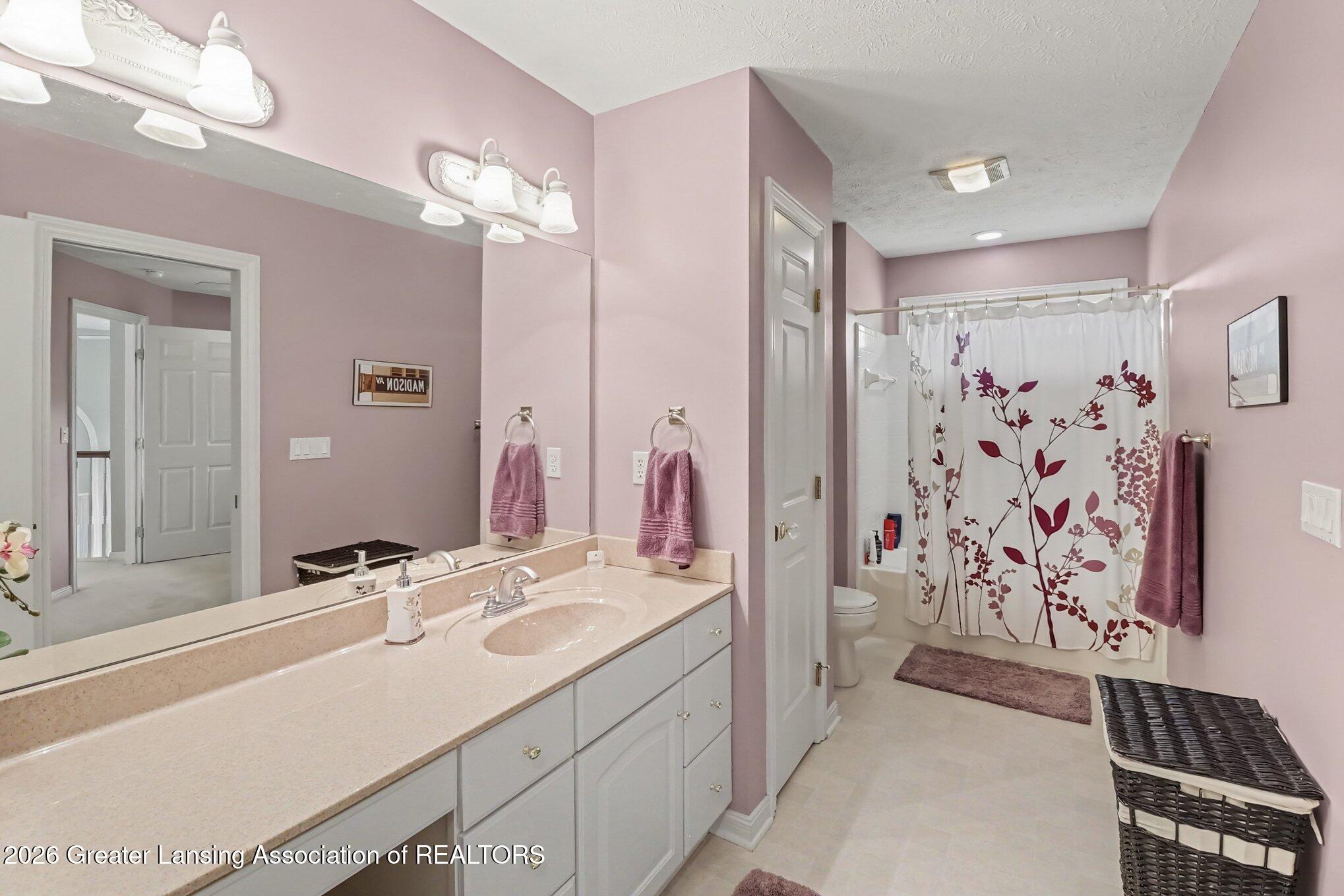 Bathroom with a long double vanity and a tub behind a floral shower curtain.