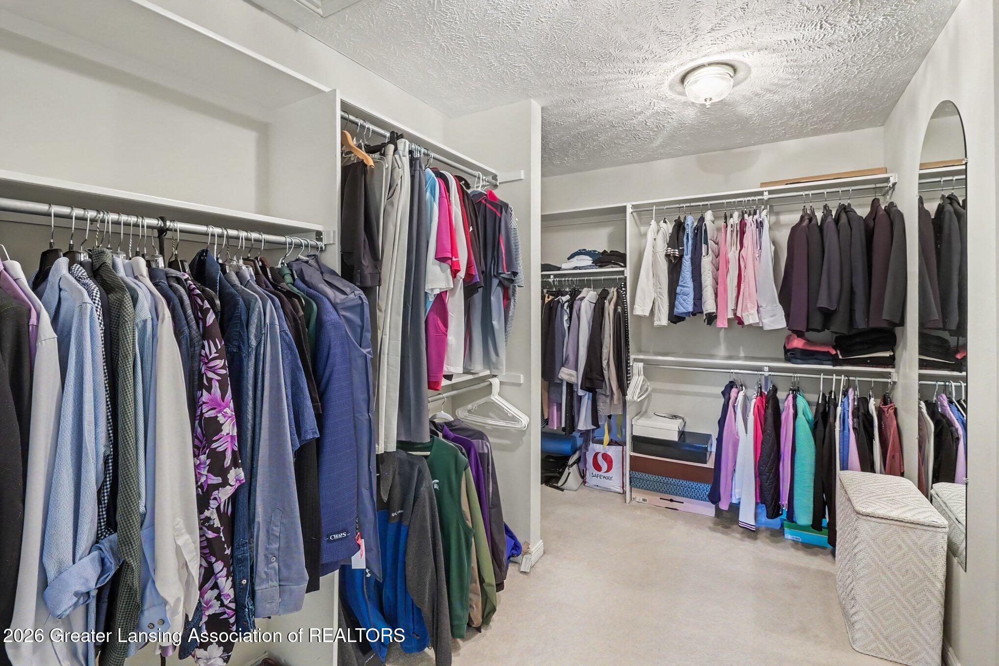 Walk-in closet with extensive clothing racks, a full-length mirror, and a woven hamper.
