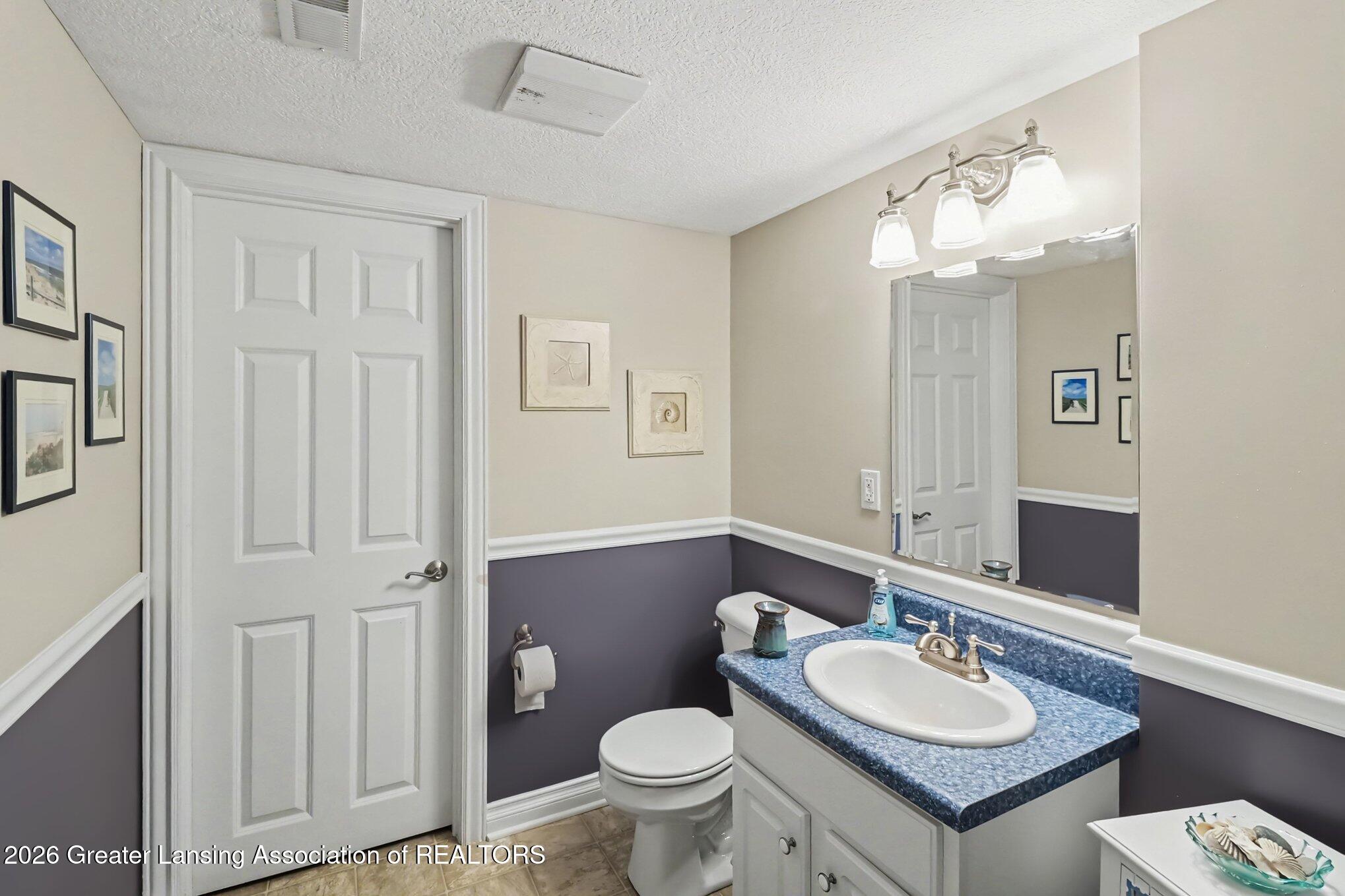 Bathroom with blue-speckled vanity countertop, large mirror, and two-tone walls.