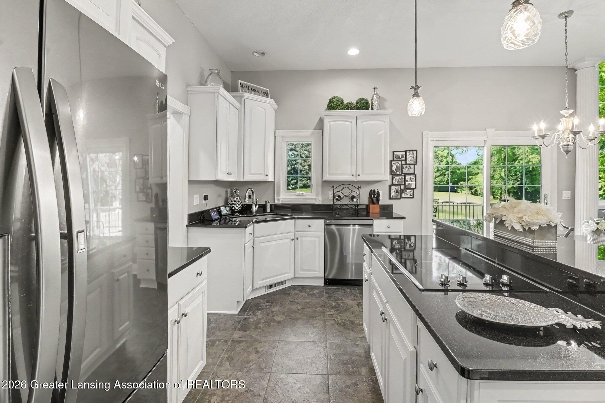 Kitchen with white cabinets, black granite counters, stainless steel appliances, and an island cooktop.