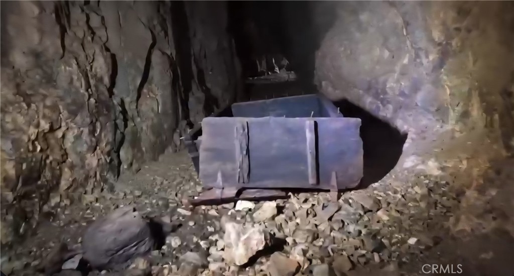 Rocky underground cavern with an old metal mining cart amid rubble.