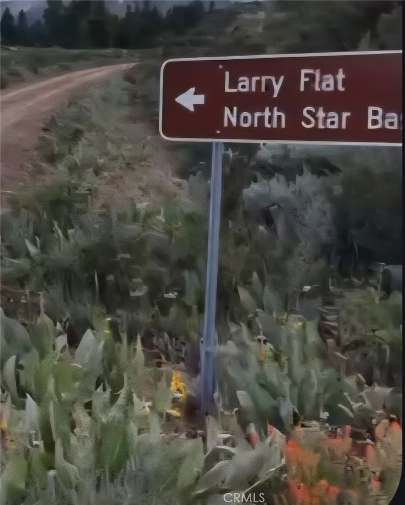 Roadside sign pointing toward Larry Flat and North Star Ba, beside a dirt road through scrubland.