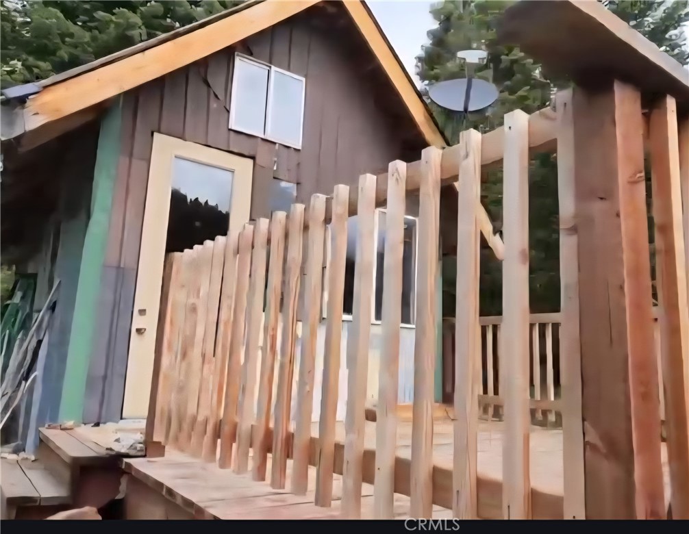 Cabin exterior with a steep gabled roof and unfinished wooden porch railing.