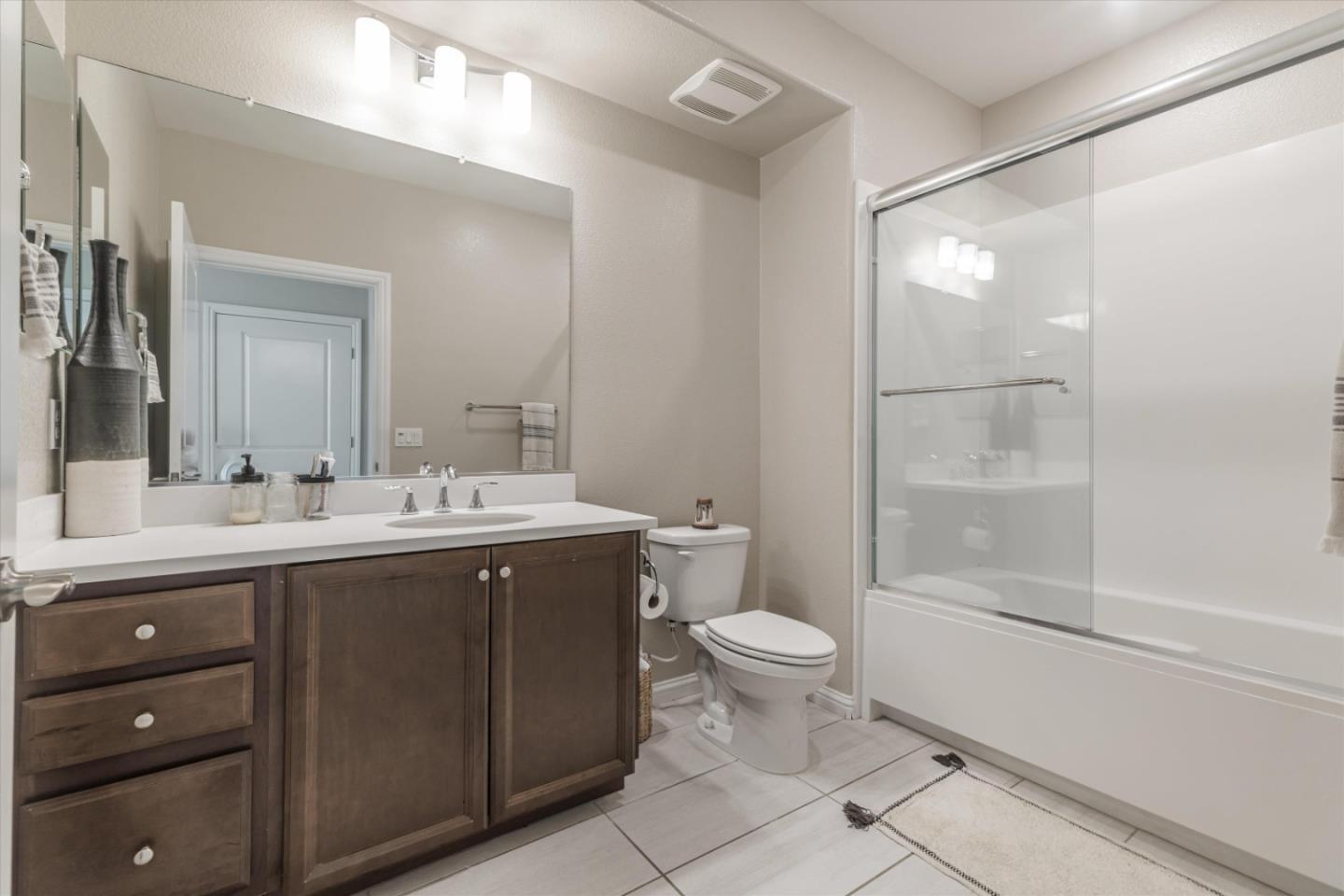 Bathroom with a dark wood vanity and a bathtub behind sliding glass shower doors.