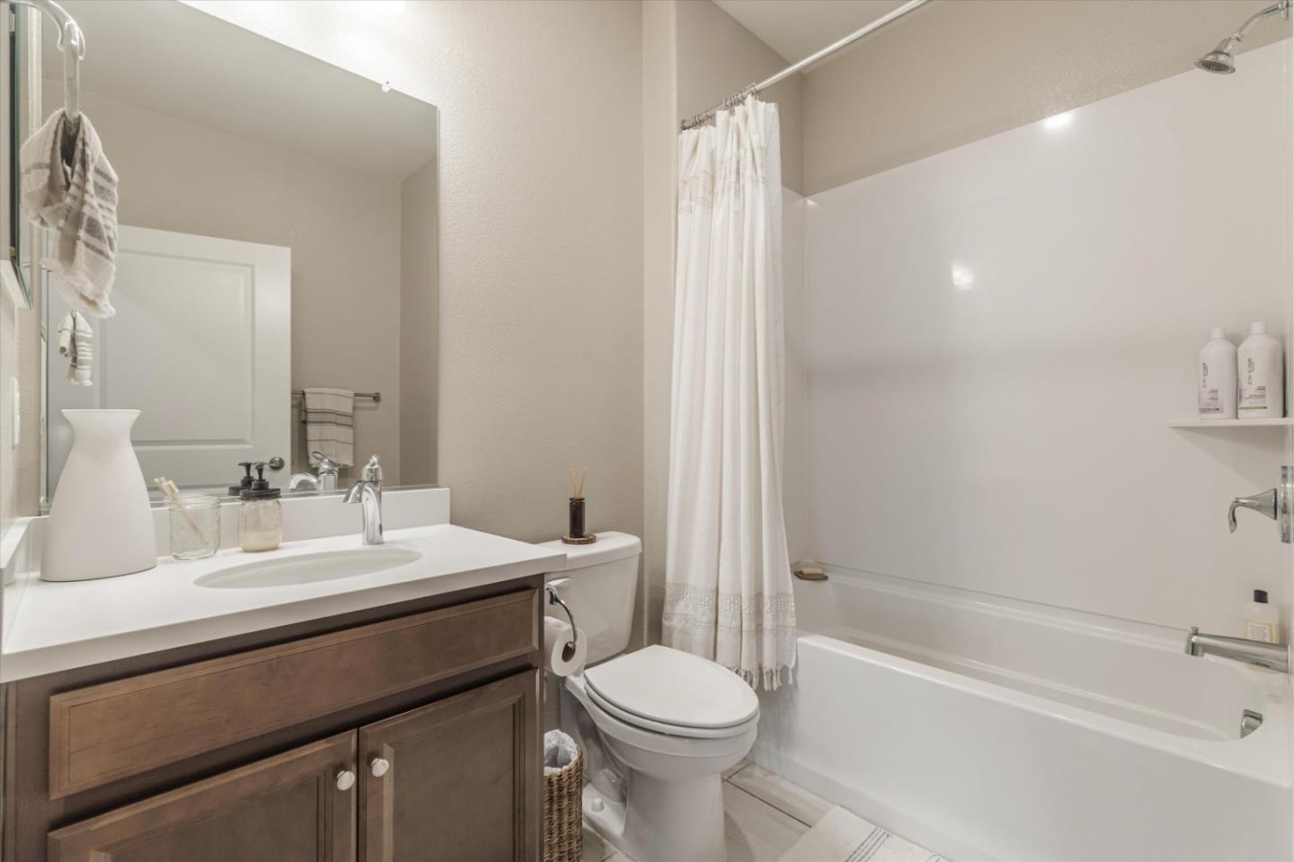 Bathroom with a dark wood vanity, large mirror, and bathtub behind a white shower curtain.