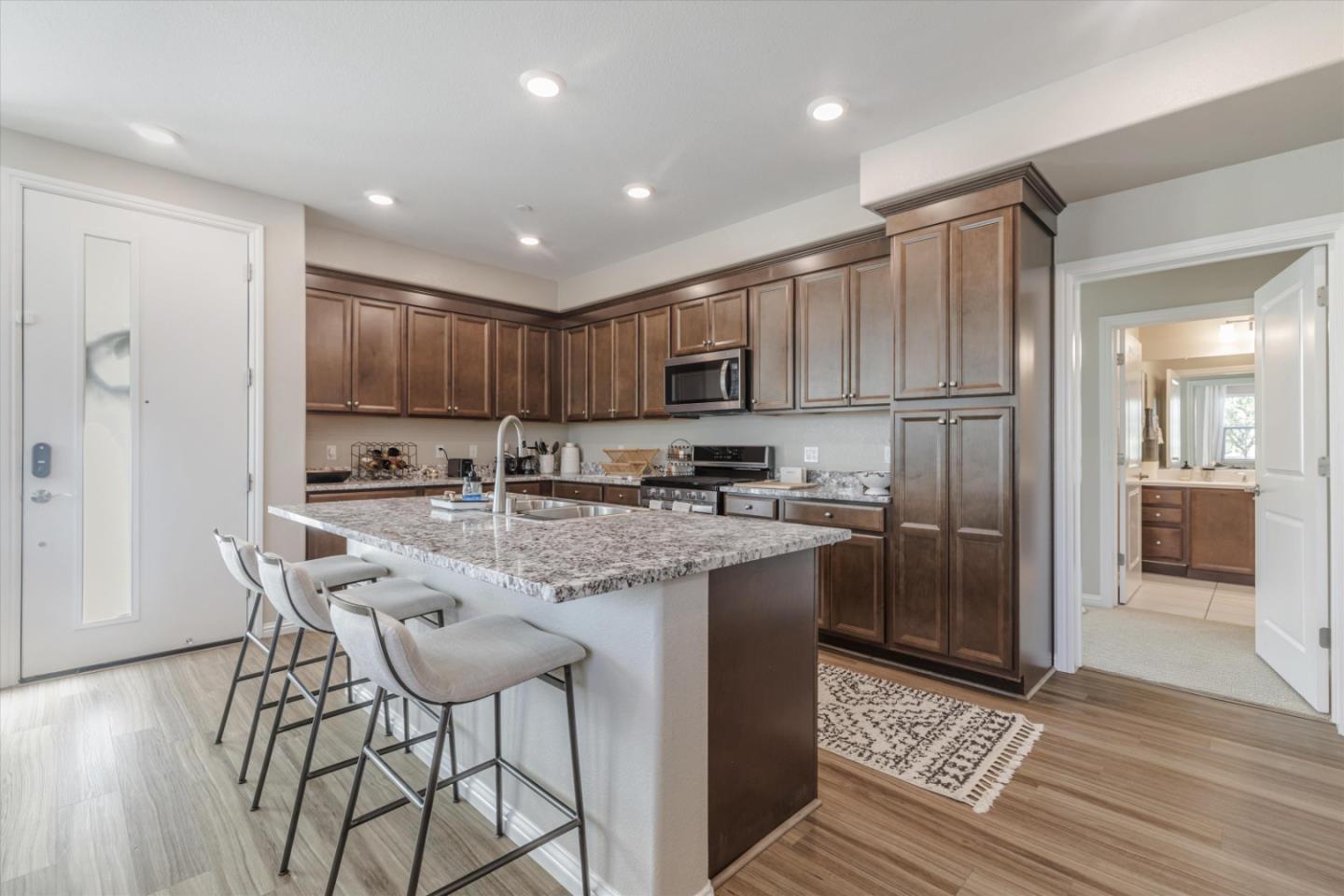 Kitchen with a granite island, dark wood cabinets, and breakfast bar stools.