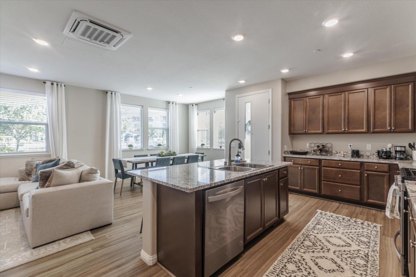 Open-plan kitchen with granite island and dark wood cabinetry adjoining a bright living and dining area.
