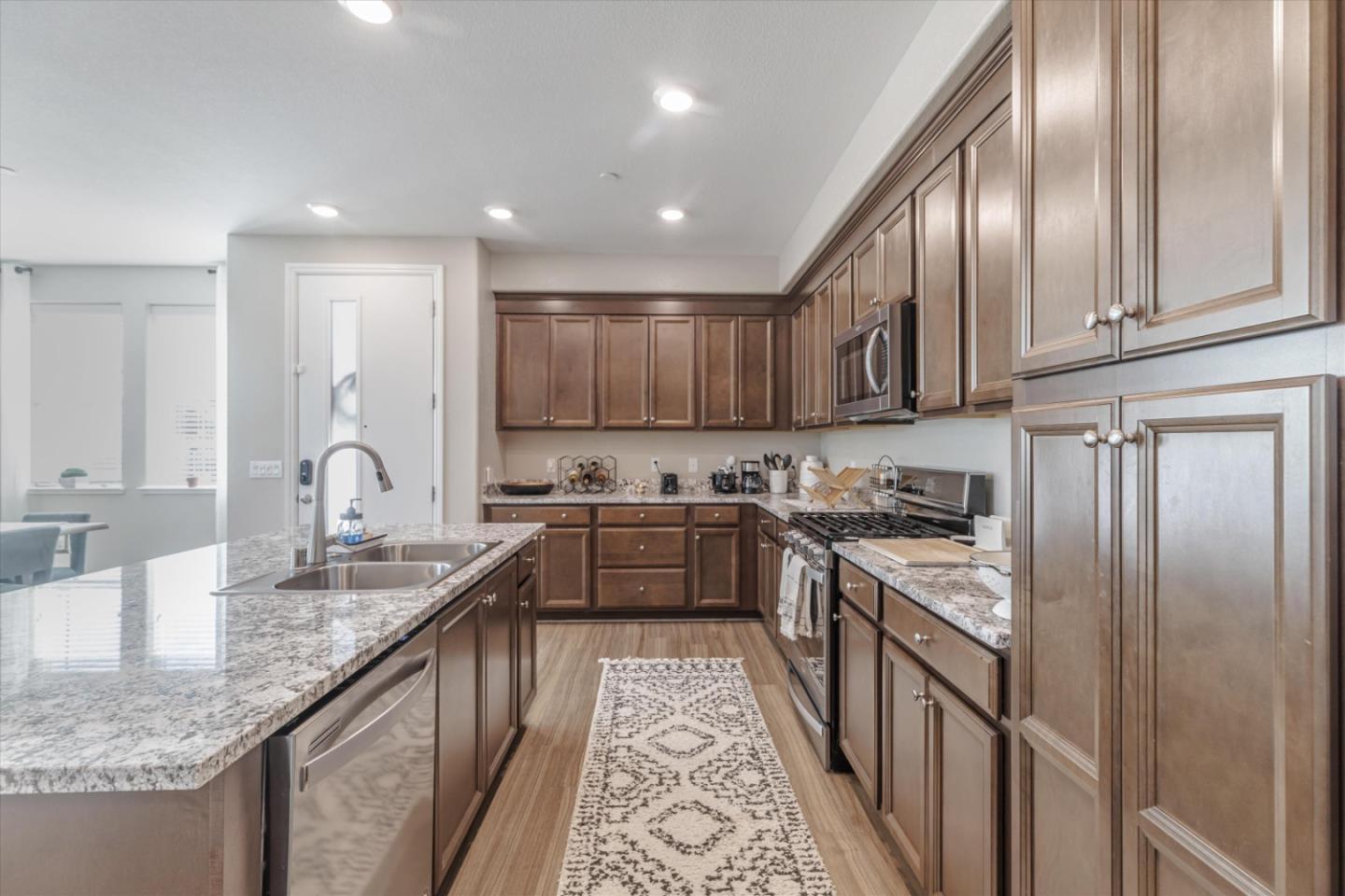 Kitchen with dark wood cabinetry, granite counters, and a large island with a double-basin sink.