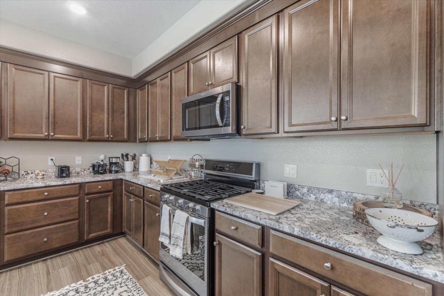 Kitchen with brown cabinetry, granite counters, and a stainless steel gas range.
