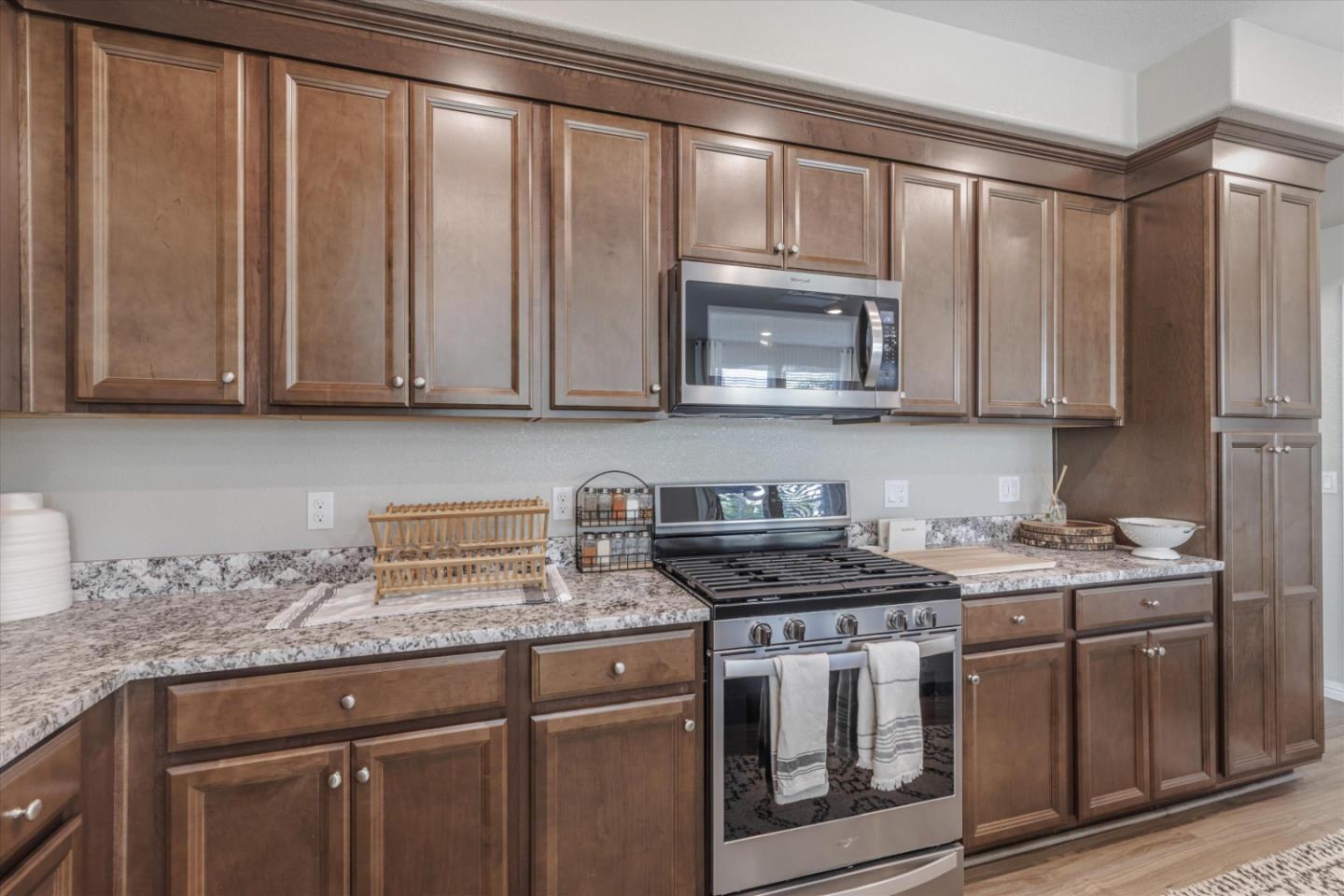 Kitchen with warm brown cabinetry, granite countertops, and a stainless steel gas range.
