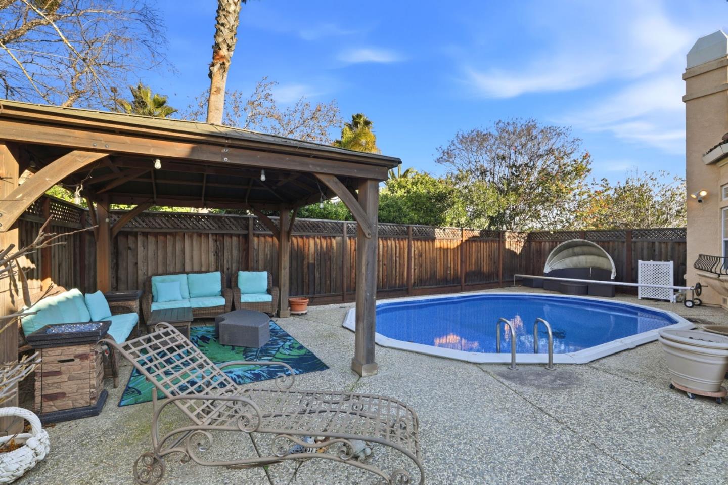Backyard pool beside a covered wooden pergola with turquoise outdoor seating.