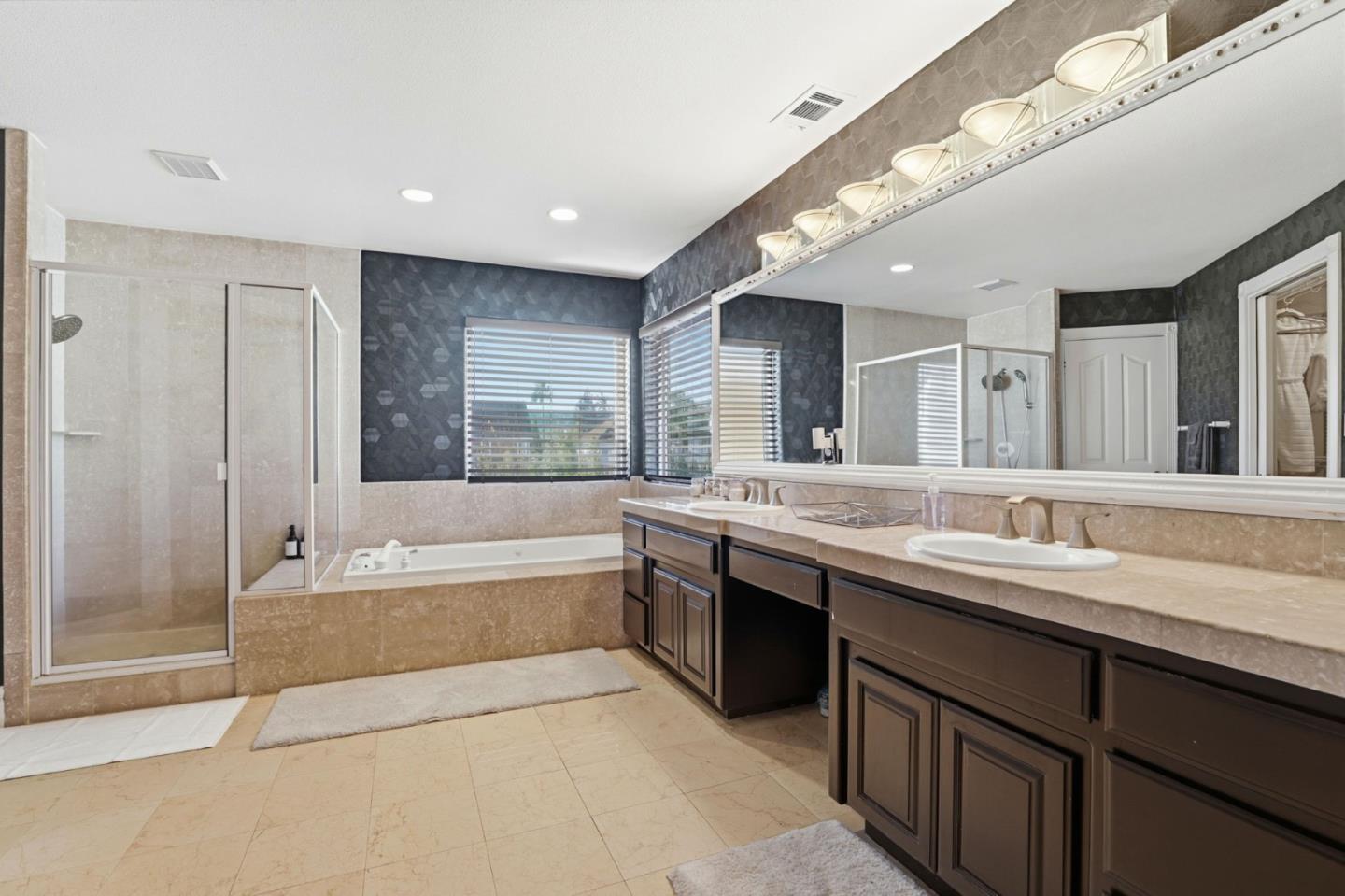 Spacious bathroom with a double vanity, soaking tub, and glass-enclosed shower.