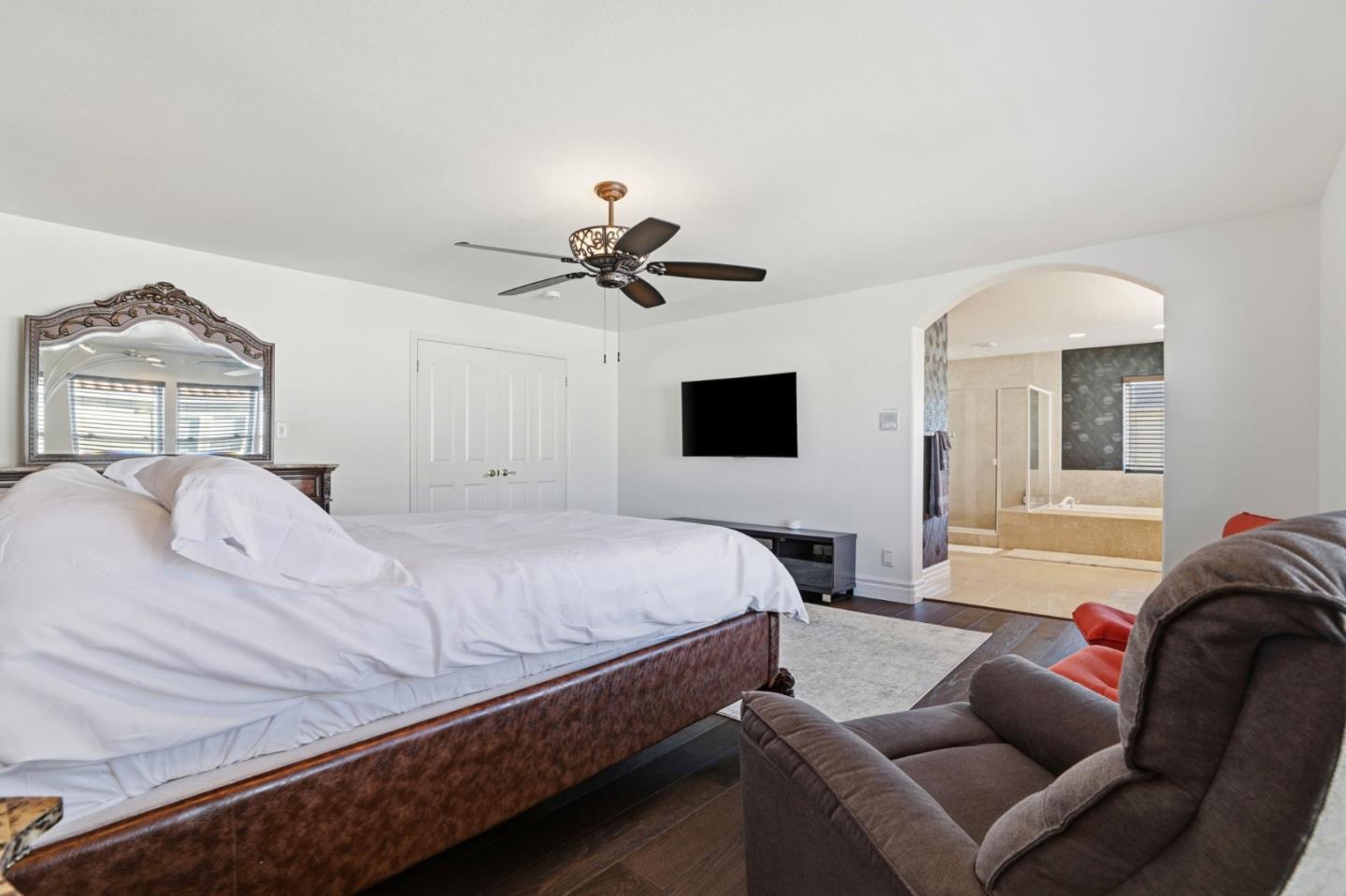 Bedroom with a large bed and sitting area, opening onto an en-suite bathroom.