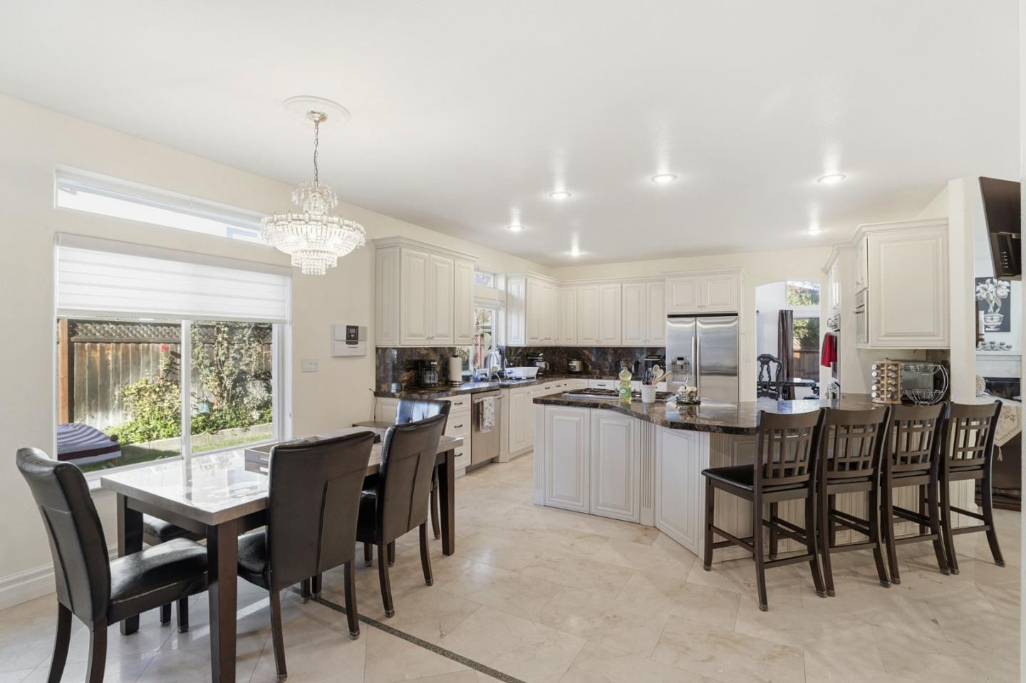 Open kitchen and dining area with a large island, white cabinets, and sliding glass doors.
