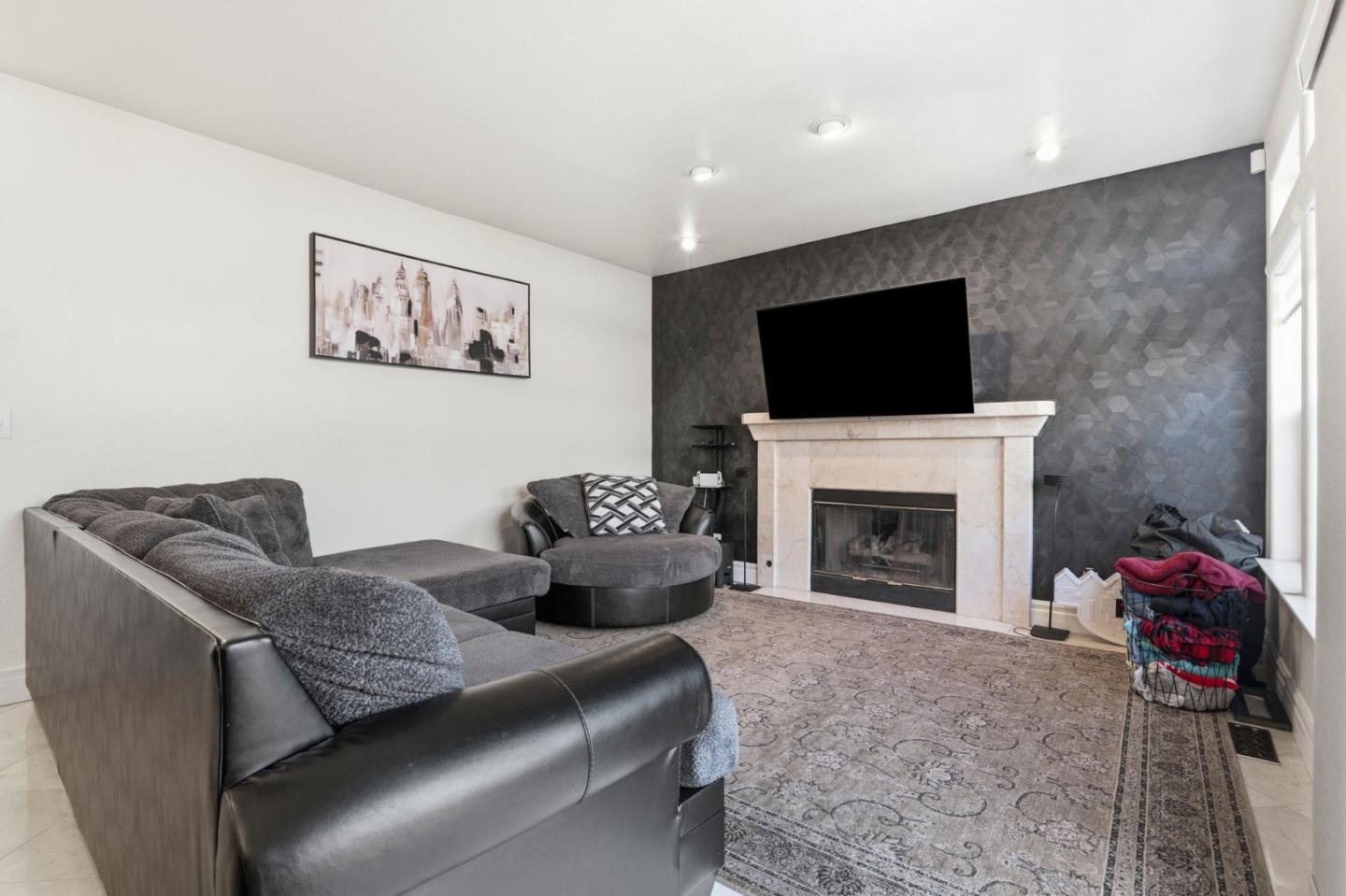 Living room with a gray sectional sofa, fireplace, and dark geometric accent wall.