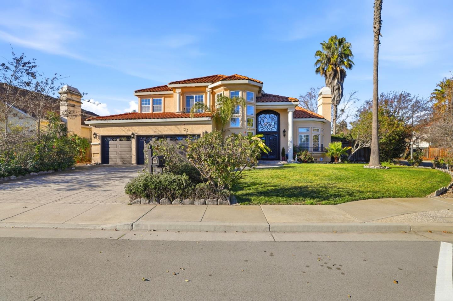 Two-story stucco home with a red tile roof, ornate dark entry door, and attached two-car garage.