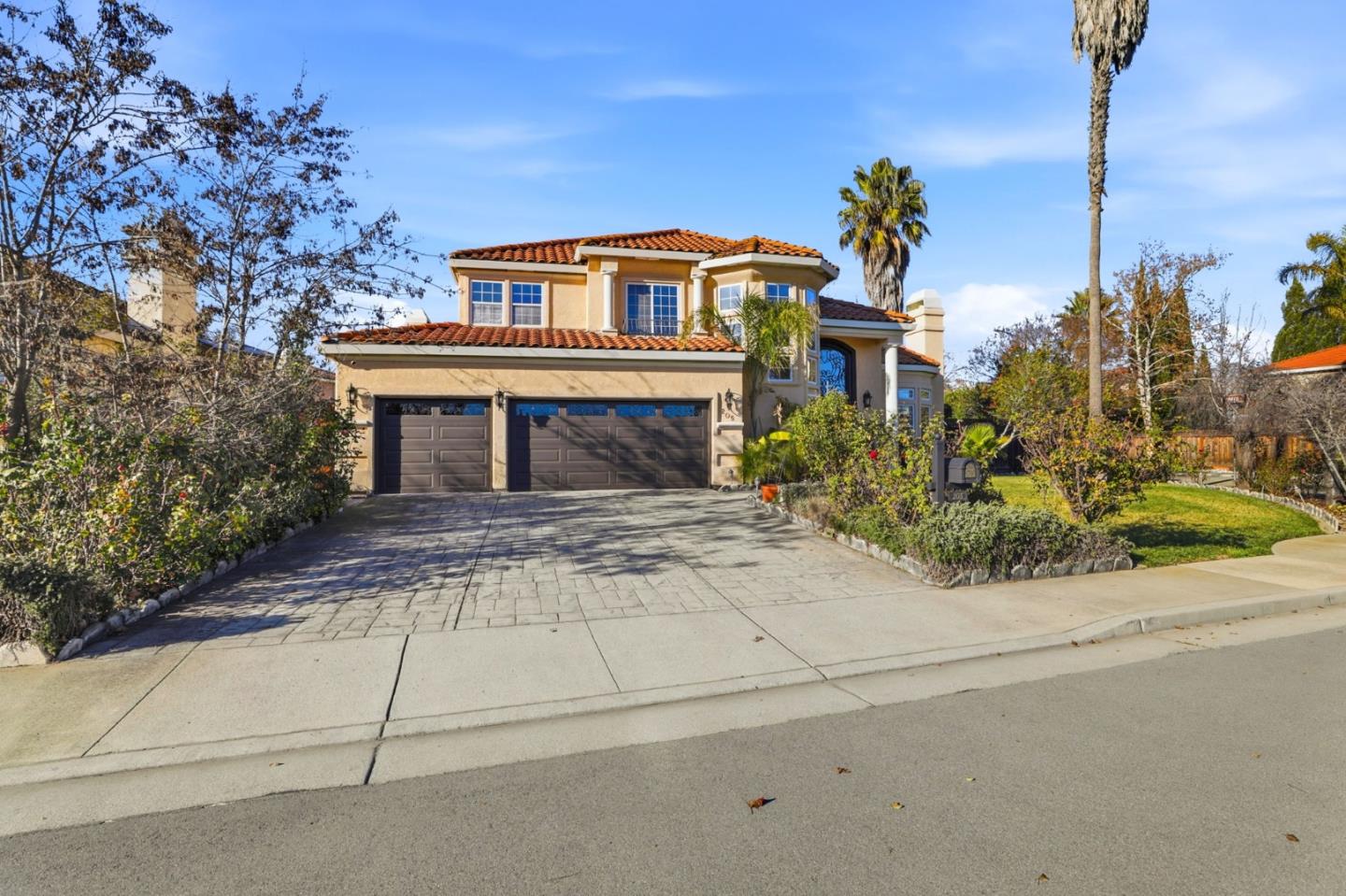 Two-story stucco home with a red tile roof, double garage, and broad paved driveway.