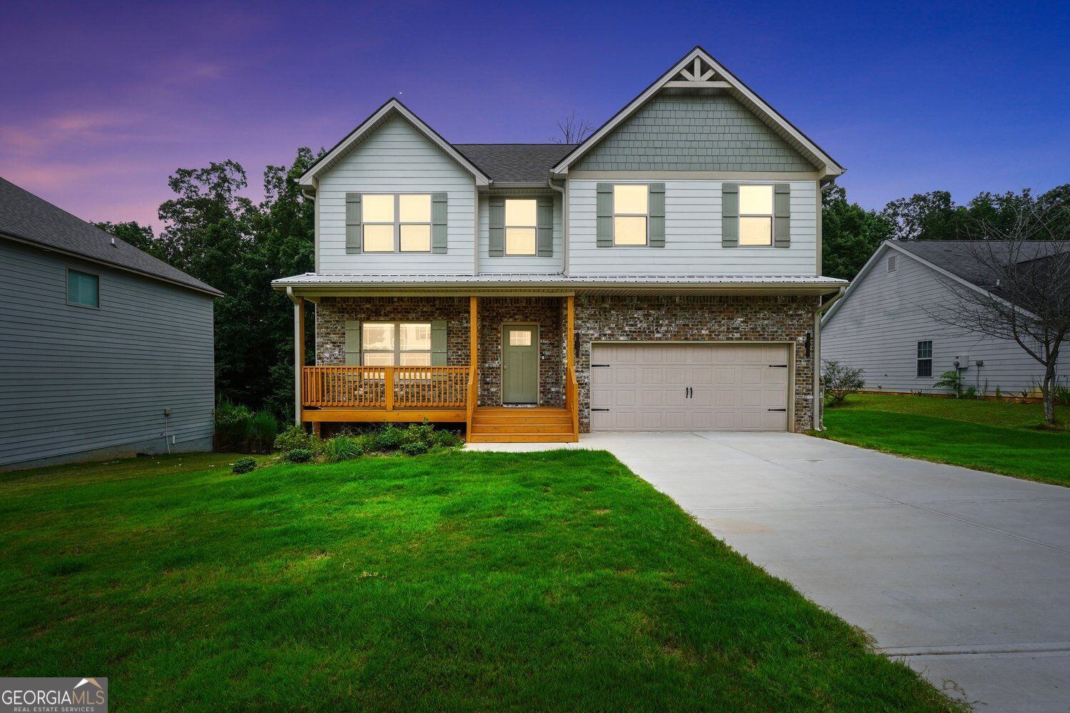 Two-story white and brick house with a covered porch and attached garage at dusk.