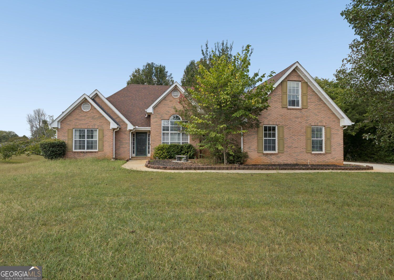 Red brick home with multiple gables, tan shutters, and a broad front lawn.