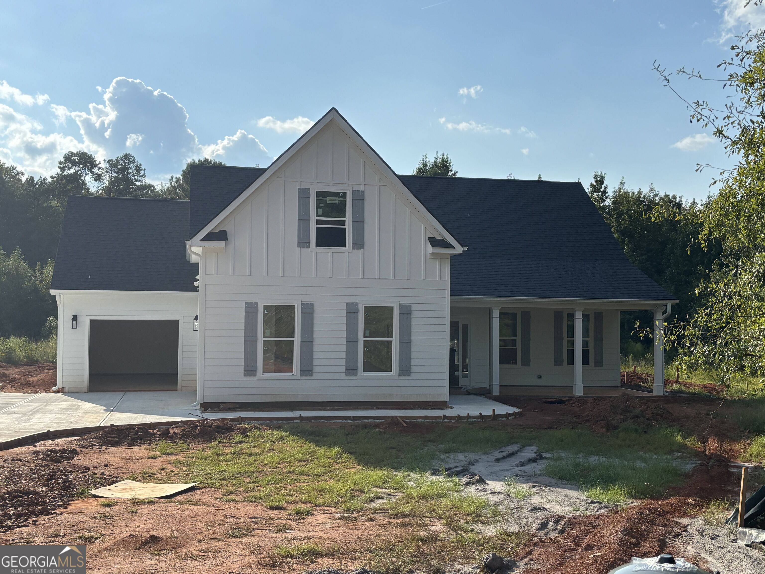 White two-story house under construction with a front gable, attached garage, and covered porch.