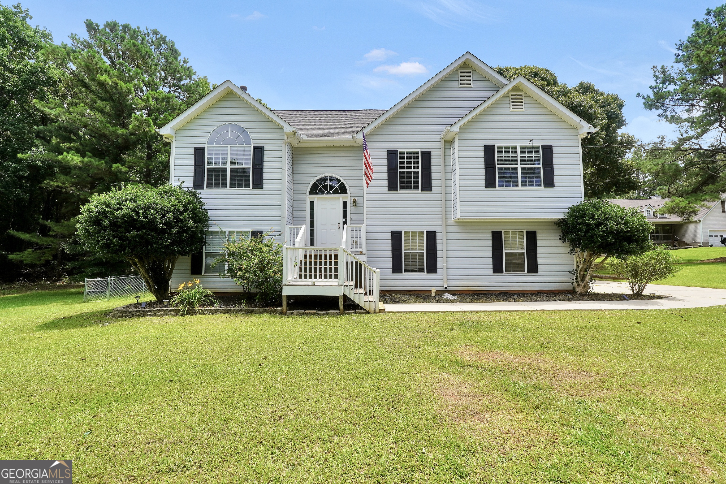 White two-story house with black shutters, an arched entry, and a broad front lawn.