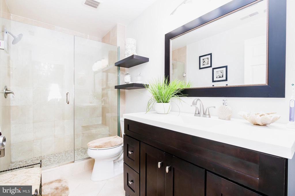 Bathroom with a glass shower, dark wood vanity, and large framed mirror.