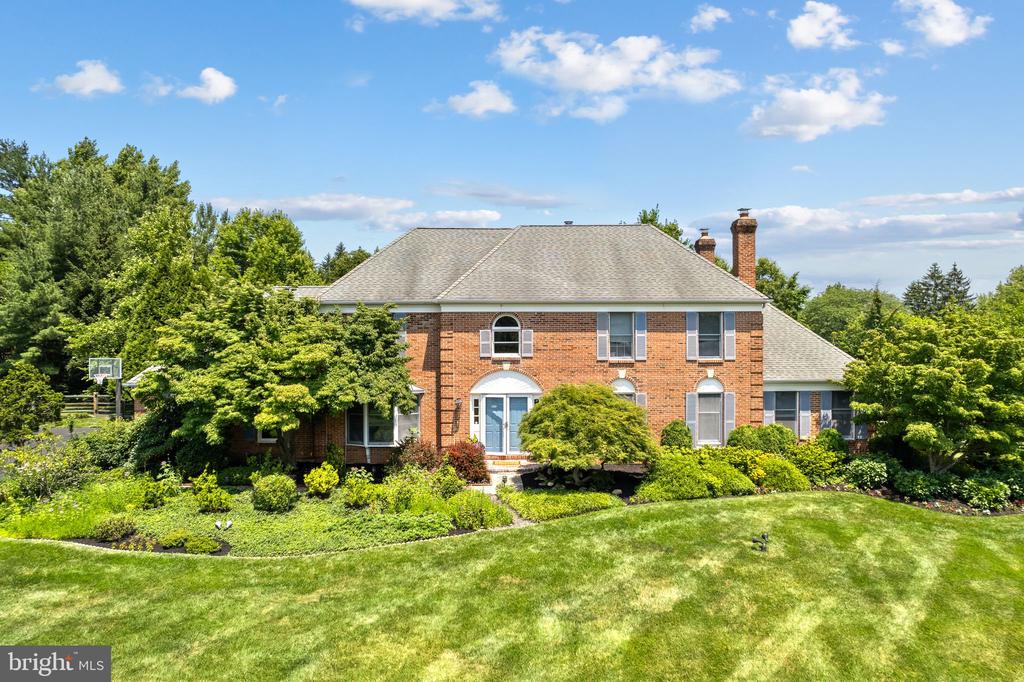 Red-brick two-story house with a pale blue front door, landscaped garden, and broad lawn.