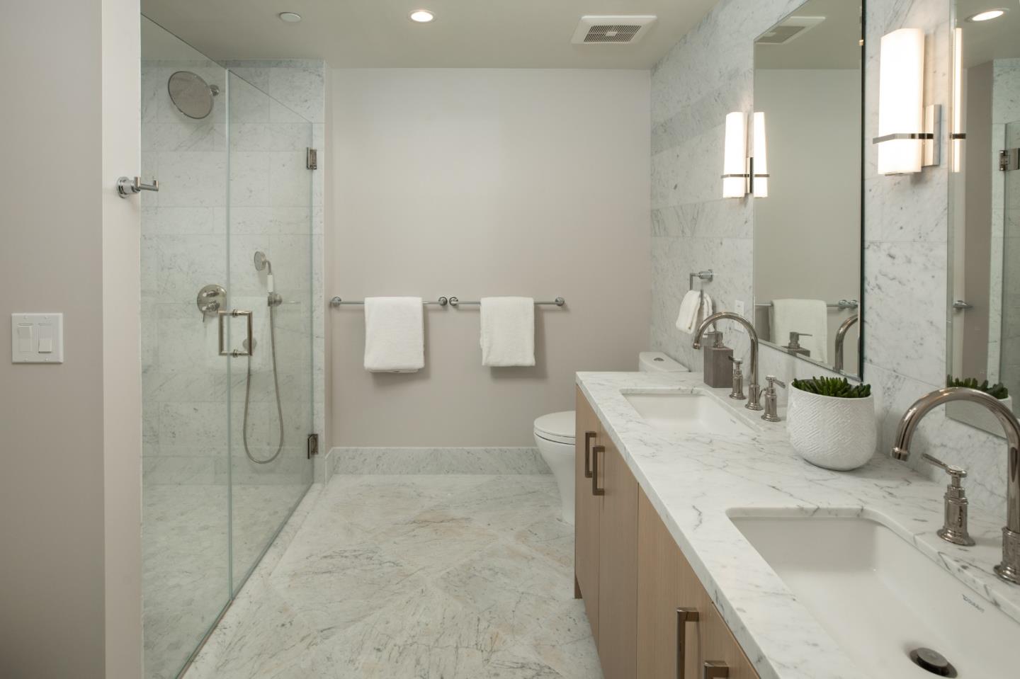 Marble bathroom with a glass shower and double-sink vanity.