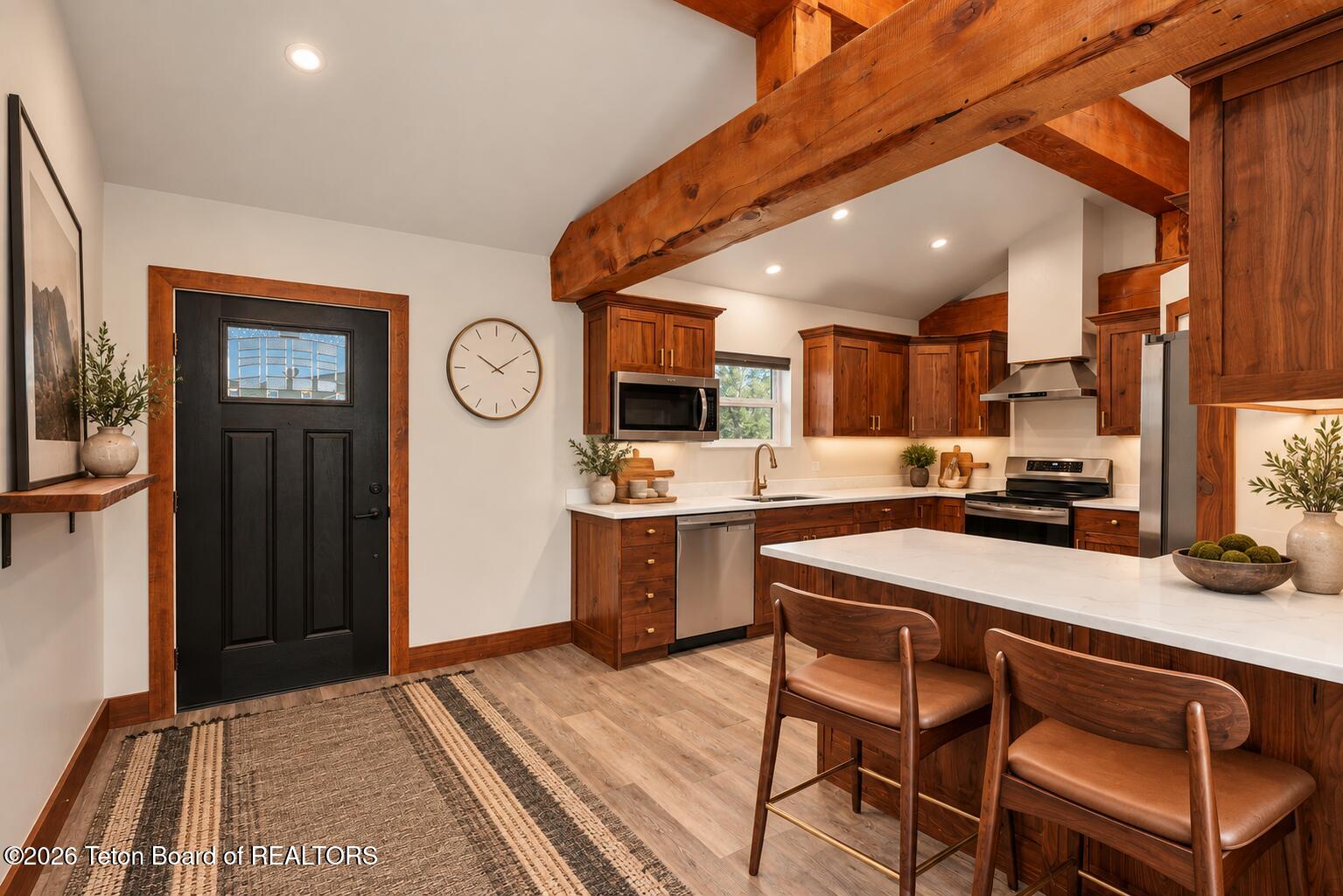 Kitchen with rich wood cabinetry, exposed beams, and a large island with seating.