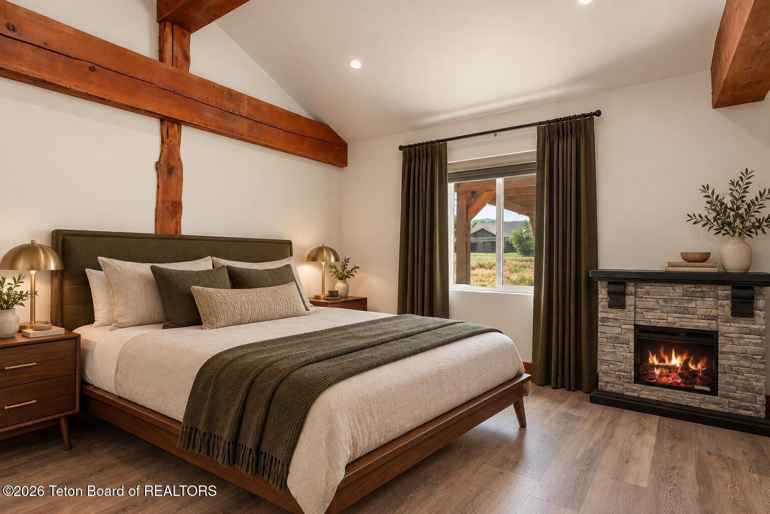 Bedroom with exposed timber beams, a stone fireplace, and a large bed.