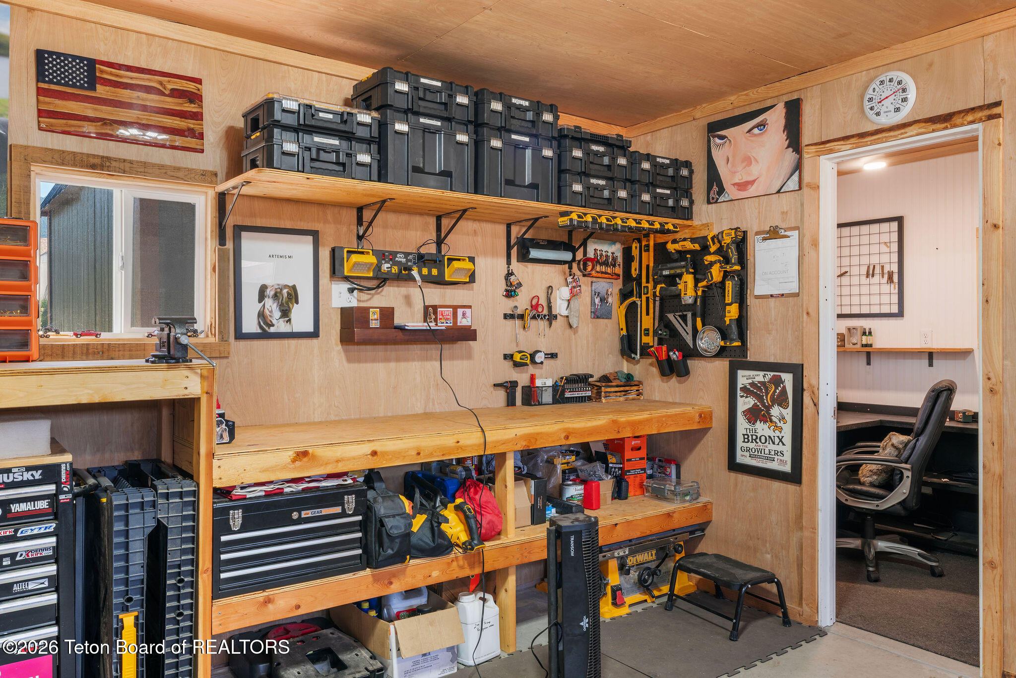 Workshop with organized power tools, wooden workbench, storage cases, and adjoining office.