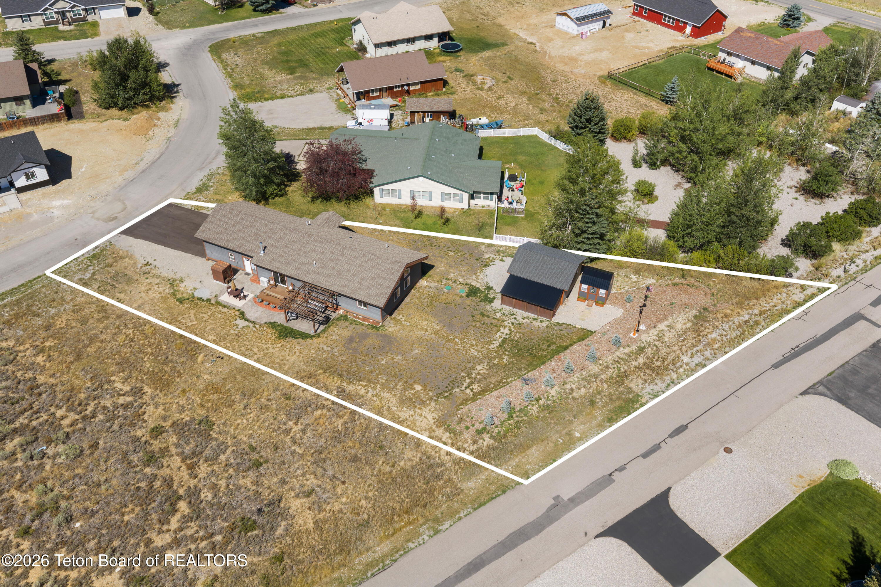Aerial view of a single-story home and two outbuildings on a large outlined lot.