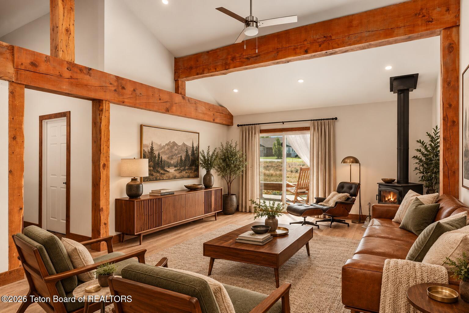 Living room with exposed timber beams, leather seating, and a black wood-burning stove.
