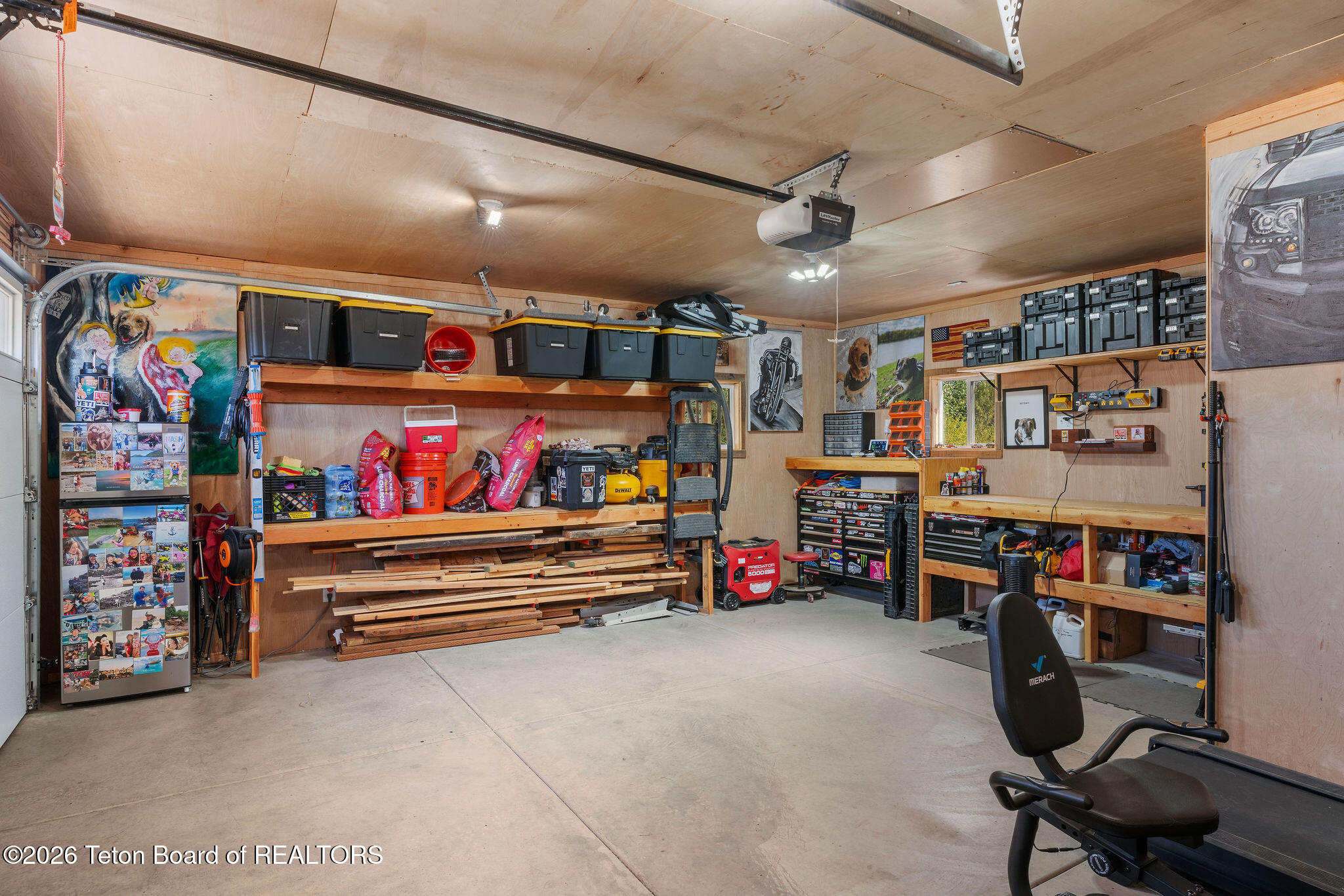 Garage workshop with extensive shelving, stored lumber, tool chests, and a workout bench.