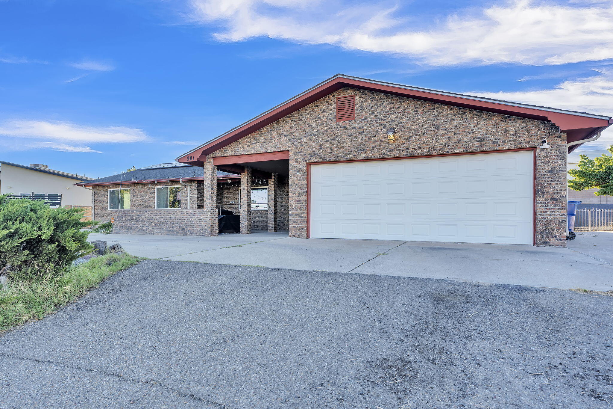 Brick house with red roof trim, a covered entry, and a wide white garage door.