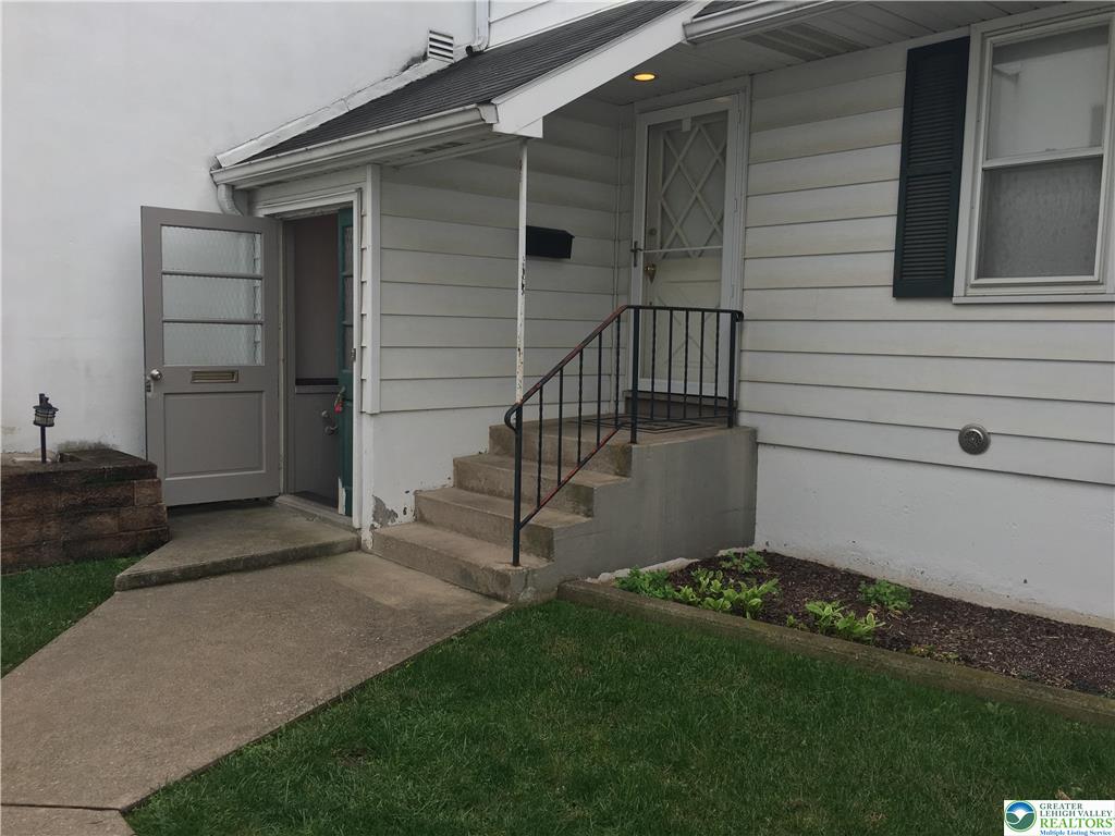 Home exterior entrance with concrete steps, black railings, and an open door beside the basement entrance.