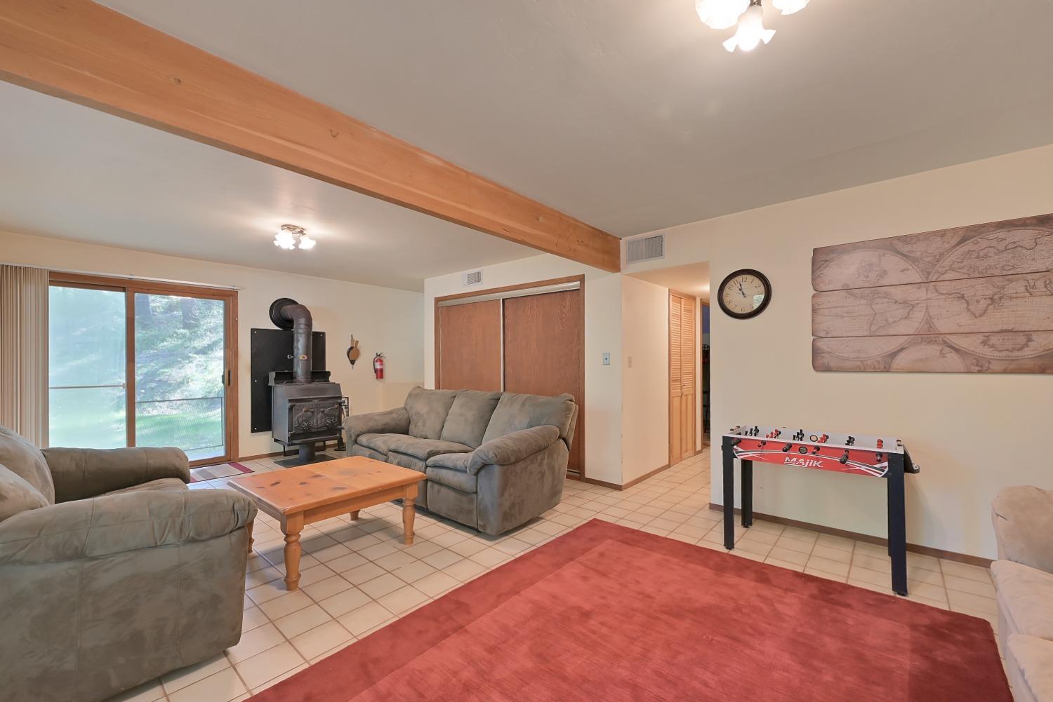 Living room with gray sofas, a wood-burning stove, and a foosball table.