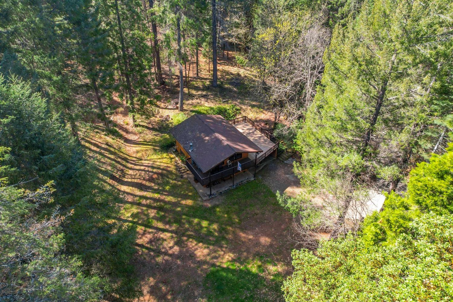Aerial view of a wood home and broad deck in a wooded clearing.