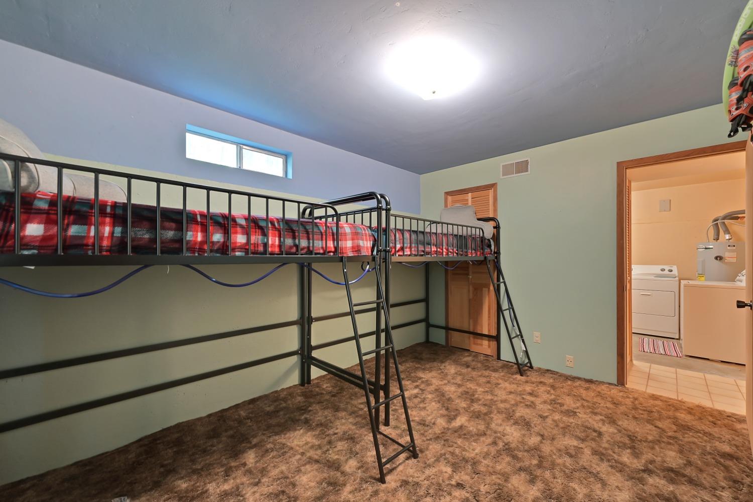 Bedroom with a metal loft bunk bed and doorway to a laundry area.
