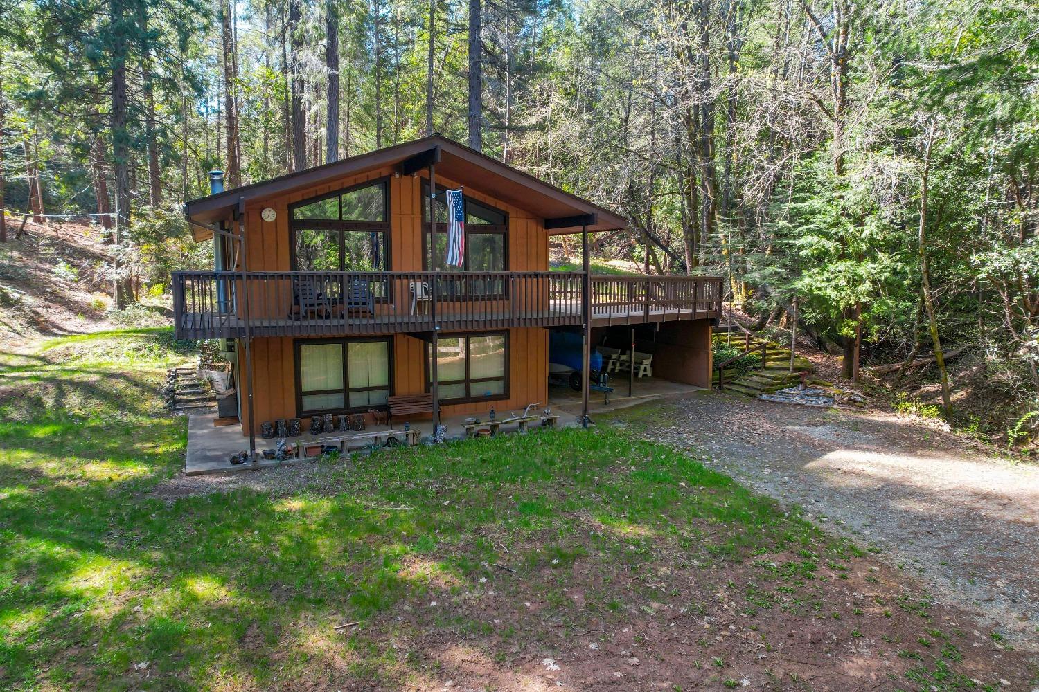 Wood-sided home with a broad deck nestled among tall trees.