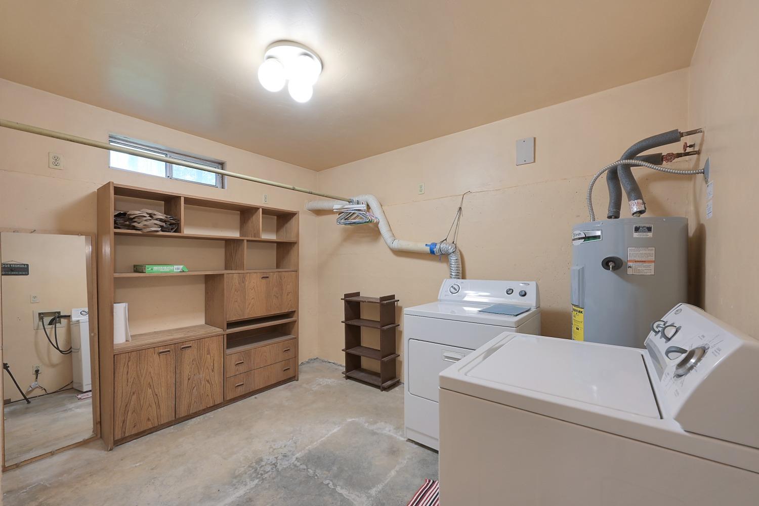 Laundry room with washer and dryer beside built-in wooden storage cabinets.