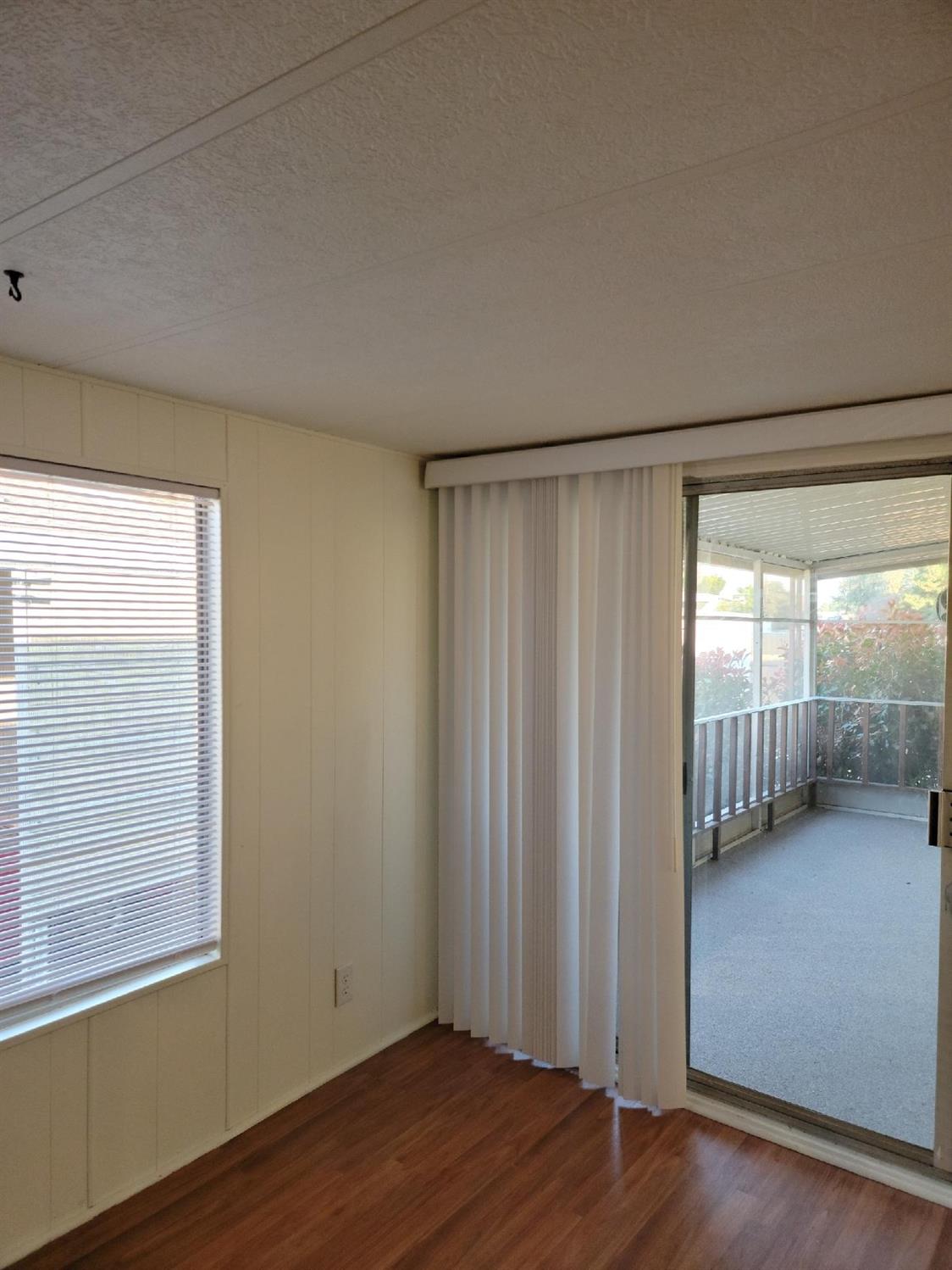 Empty room with wood flooring and a sliding glass door to a screened porch.