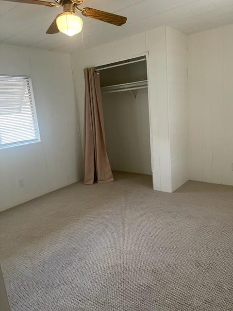 Vacant bedroom with a curtained closet, window blinds, and a ceiling fan.