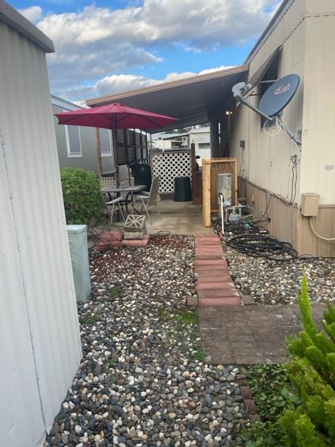 Covered patio with a red umbrella, gravel landscaping, and a stepping-stone path.