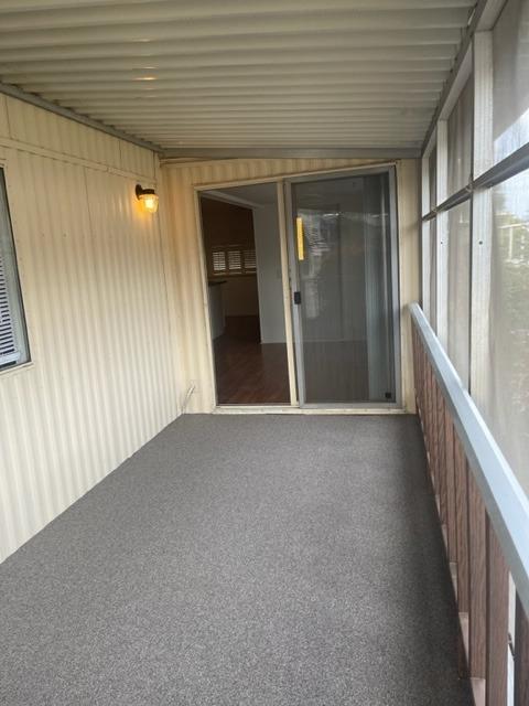 Covered screened porch with gray carpet, a sliding glass door, and a railing along the windows.