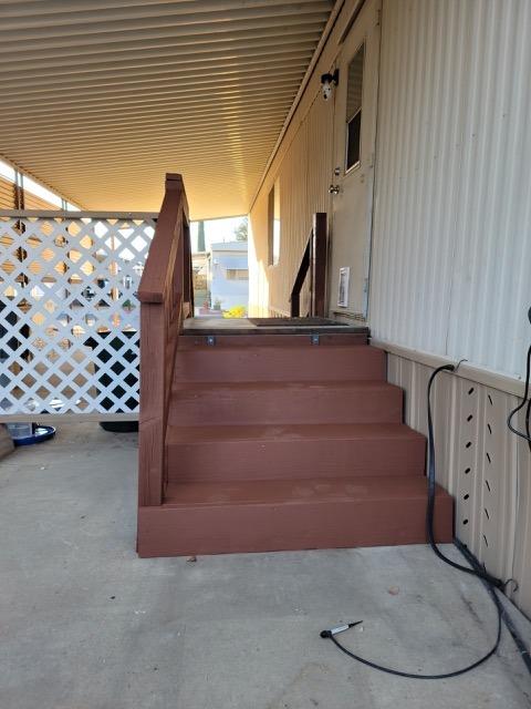 Covered porch with brown wooden steps, white lattice screening, and a concrete floor.