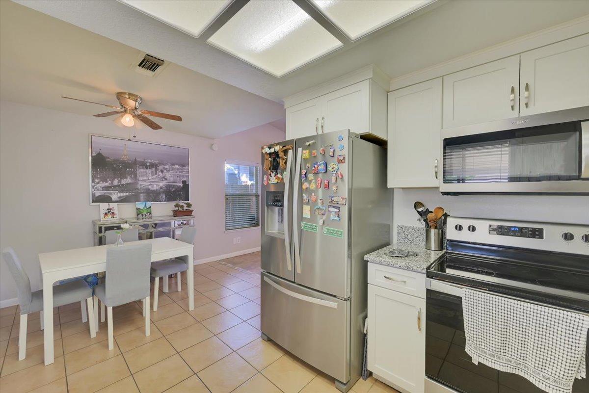 Kitchen and dining area with white cabinets, stainless steel appliances, and a white table.