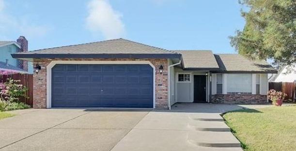 Single-story home with a dark blue double garage door and wide concrete driveway.